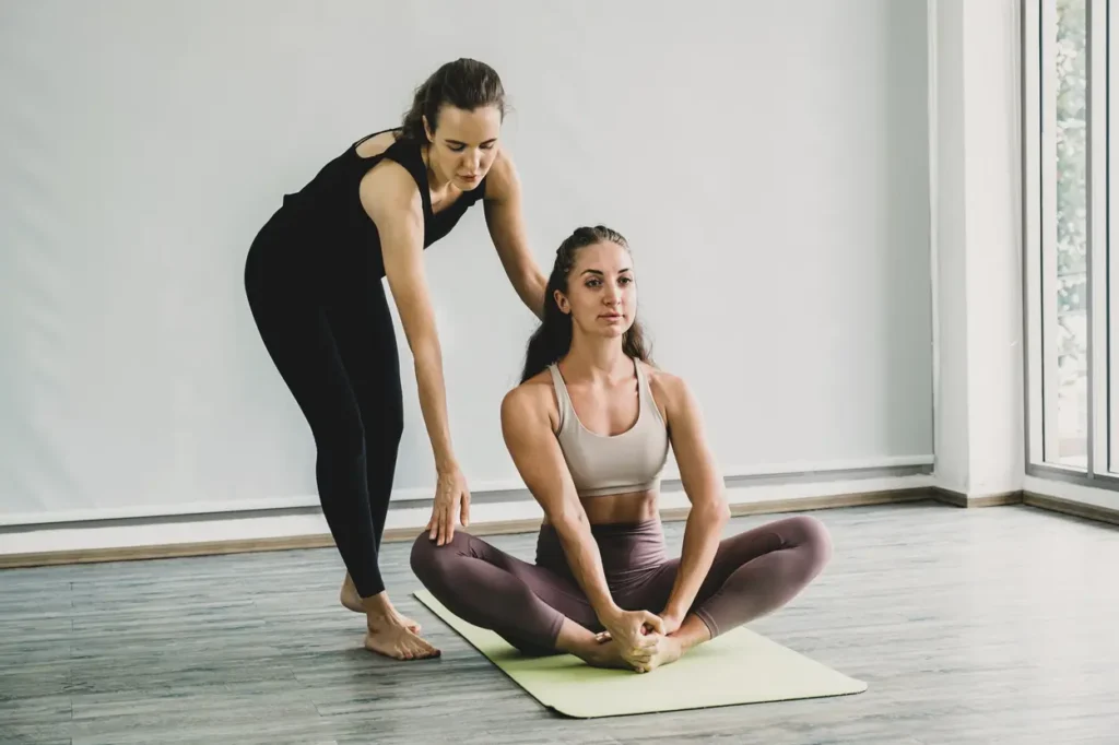 Professeur de yoga expliquant une posture à ses élèves dans un environnement paisible, illustrant le salaire moyen d’un enseignant de yoga.
